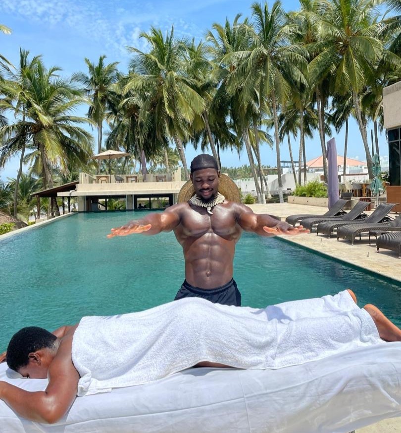 A poolside massage session in progress, with a therapist massaging a client's back while they float on a pool lounger
