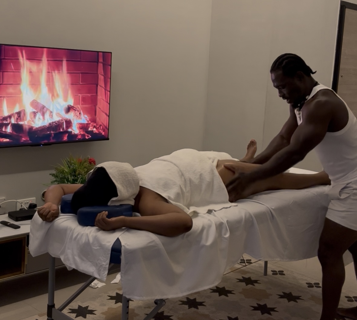A serene spa setting with a therapist applying a hot stone massage to a client's back, surrounded by candles and soothing decor